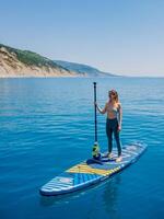 July 15, 2021. Anapa, Russia. Woman on stand up paddle board at blue sea. Woman on sup board Gladiator Pro in sea. Aerial view photo