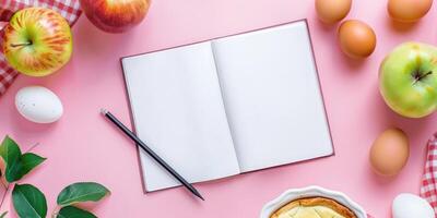 Cookbook open mockup on pink table with apples, pie and eggs. Ingredients for home baking. photo