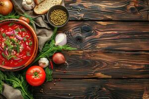 A plate of beet root soup borscht on a wooden table with vegetables, top view. Homemade food background with copy space photo