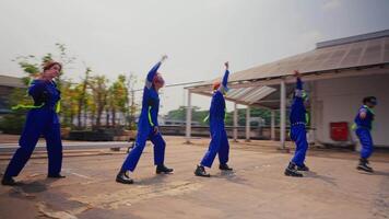 grupo do trabalhadores dentro uniformes fazendo uma coordenado dança ao ar livre. video