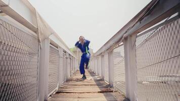 Stylish person in blue jumpsuit posing confidently on an urban rooftop with industrial backdrop. video