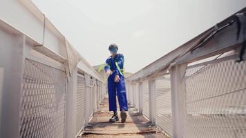 à moda pessoa dentro azul macacão posando com confiança em a urbano telhado com industrial pano de fundo. video