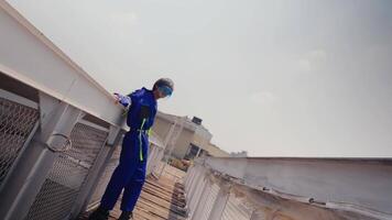 trabajador en azul overoles y la seguridad casco inspeccionando al aire libre sitio video