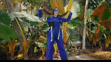 Woman in blue suit taking a selfie with tropical plants in a greenhouse. video