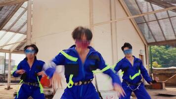 gens dans bleu uniformes avec néon ceintures, suggérant mouvement ou dansant activité, peut-être dans une atelier ou industriel paramètre. video