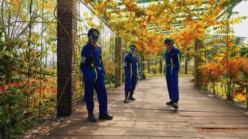 Three people in blue uniforms with VR headsets walking in an autumnal garden setting. video