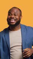 Vertical Portrait of joyful cheerful african american man celebrating, showing positive emotions. Delighted BIPOC person thrilled by achievement, cheering and gesticulating, studio background, camera A video