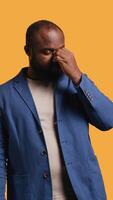 Vertical African american man feeling exhausted from overworking and lack of sleep, suffering from headache and yawning, studio background. Tired BIPOC person feeling migraine from fatigue, camera B video