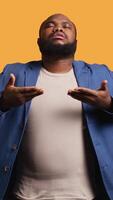 Vertical African american man inhaling and exhaling to relax and gain positive energy, eliminating stress. BIPOC person doing breathing exercises for wellbeing, studio background, camera B video