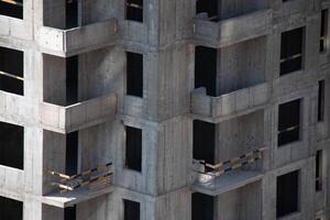 Exterior of Concrete Wall Frame of Building under Construction. Architectural origin of Structure. Monolithic box with holes for windows and floor slabs on sunny day at Construction Site photo