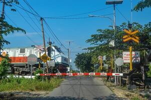 The train crossing was closed because an economy train was passing by. The motorcyclist seemed to stop and wait, Indonesia, 4 May 2024. photo