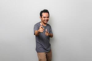 a happy asian man in gray is pointing towards the front isolated on white background photo