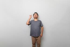 an asian man in gray is getting an idea while looking and pointing upwards isolated on white background photo