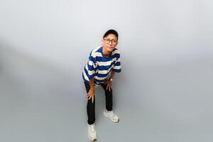 A man in a striped shirt and glasses is standing on a grey background photo