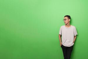 un hombre en un gris camisa soportes en frente de un verde pared foto