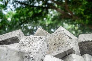 wallpaper texture or pattern or background of a messy pile of paving blocks with copy space on a bokeh and blurred green plant background photo