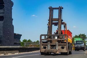 un máquina elevadora paso en el carretera, Indonesia, dieciséis mayo 2024. foto