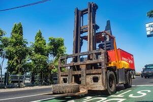 un máquina elevadora paso en el carretera, Indonesia, dieciséis mayo 2024. foto