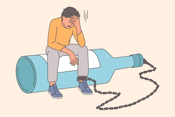 Man suffers from alcohol addiction or hangover, sits on large bottle with chain on leg
