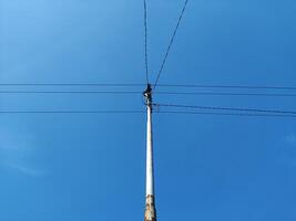 Low angle view of electricity pylon against blue sky photo