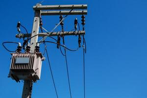 Electrical poles equipped with large power transformers The background is a bright blue sky. photo