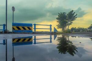 puddles of water on the highway after rain in the afternoon with views of the twilight sky and reflections in the water photo