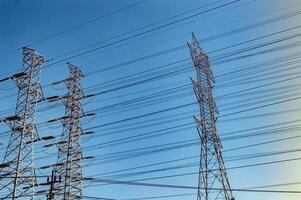 several high voltage power towers against a bright blue sky background photo