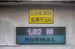 The LED screen contains information indicating the water level of the Bengawan Solo River to prevent flooding in the rainy season. Translation No entry except officers photo