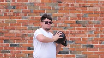 sports and leisure. strong Caucasian man working out using kettlebell in the park, brick wall background video