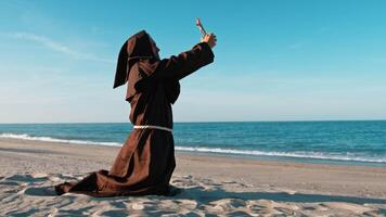 monk prays with crucifix on the beach video