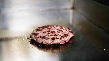 Beef burger cooks on steel plate video
