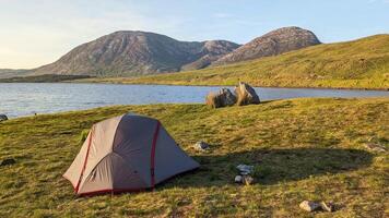 Camping tent by Lough Inagh, Connemara national park, county Galway, Ireland, lakeside landscape scenery with mountains in background, scenic nature wallpaper video