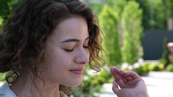 lindo jovem menina endireita cabelo dentro natureza lindo elegante modelo sorrisos, posando ao ar livre. encantador Loiras Veja dentro lento movimento. retrato do linda menina olhando para Câmera video