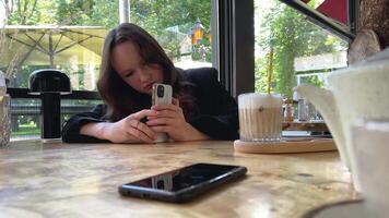 Blogger nehmen Bilder von Eis Latté. Mädchen Filme Kaffee auf Medien auf Smartphone im Cafe. Frau nehmen Bilder auf Telefon zum ihr Sozial Konten oder Geschichten. Digital Inhalt Schöpfer video