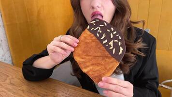 A girl blogger takes a of a flat croissant, then she bites it, tastes two servings of ice cream, cherry and vanilla, standing in the background, a delicious dessert video