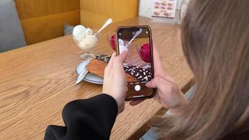 un niña blogger toma un de un plano cuerno, luego ella picaduras él, sabores dos porciones de hielo crema, Cereza y vainilla, en pie en el fondo, un delicioso postre video