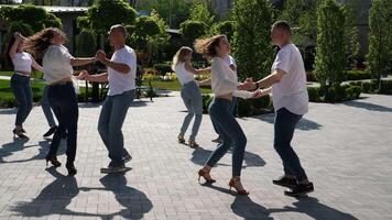 energía amor vida. suave sexy latín danza se mueve escenificado danza bachata un grupo de personas bailando en el calle el mismo movimientos blanco camisas azul pantalones adultos y joven personas de diferente siglos video