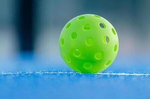 Selective focus, green pickleball ball isolated on a blue court photo