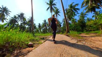 Caucasian woman runs along tropical road with palm trees in Thailand video