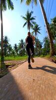 caucásico mujer carreras a lo largo tropical la carretera con palma arboles en Tailandia video