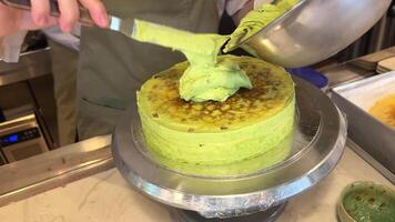 verde crema cucinando pistacchio torta diffusione con crema nel un' professionale cucina nel un' ristorante Aperto Schermo Astuccio appena preparato decorare con cioccolato e secco frutta video