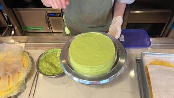 verde crema cucinando pistacchio torta diffusione con crema nel un' professionale cucina nel un' ristorante Aperto Schermo Astuccio appena preparato decorare con cioccolato e secco frutta video