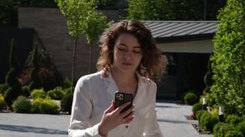 girl with a phone is walking down the street to take Smartphone to a friend, show link on Internet to rush forward with the phone video