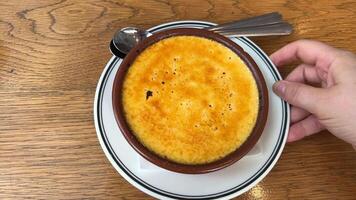 Creme brulee with sugar crust Spoon taps crisp caramel crust on creme brulee. french dessert or spanish creme catalana. Broken, cracked crust of traditional French cream dessert. Burned Trinity video