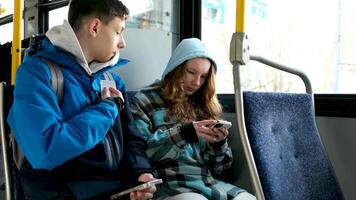 dos adolescentes en azul ropa sentar en un autobús Canadá Vancouver campanas otoño invierno primavera chándales utilizar un móvil teléfono buscar para geolocalización viaje viajeros real vida video