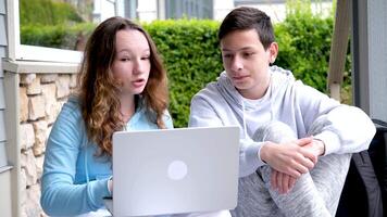 garçons adolescent les filles Faire en ligne Des classes tâche en train de regarder film social réseaux l'Internet animé bavardage émotions la sincérité adolescent garçon en riant étreinte mains autour le sien les genoux fille en portant portable video