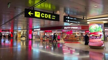 doha aeroporto Qatar 16.05.2024 negozi boutique persone in viaggio in attesa per loro aereo mossa a partire dal terminale per un altro terminale nel il riposo la zona video