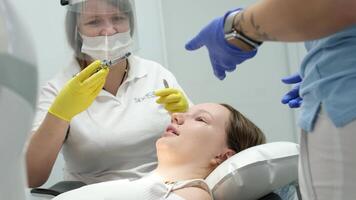 del dentista manos dando anestésico inyección a hembra paciente durante dental procedimiento en clínica. médico haciendo anestésico inyección a mujer en odontología oficina. dental tratamiento concepto. de cerca. video