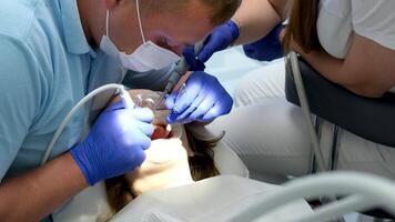 profissional dente limpeza dentista com assistente debaixo microscópio guloseimas a pacientes dentes. moderno progressivo odontologia. video