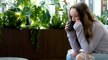 trinken Kaffee Tee Mädchen steht auf das Hintergrund von ein Wolkenkratzer und sieht aus beiseite video